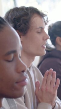 Vertical video: Following cue leading left man holding prayer hands in room with window, copy space