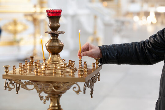 Close-up of believer hand placing candle in church candle holder