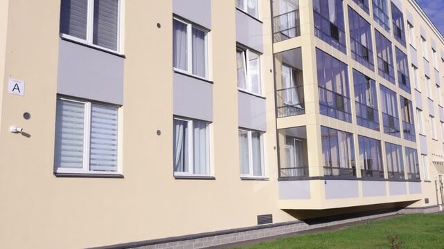 Close-up of a multi-story residential building's exterior: pale-beige panels alternate with gray accent inserts