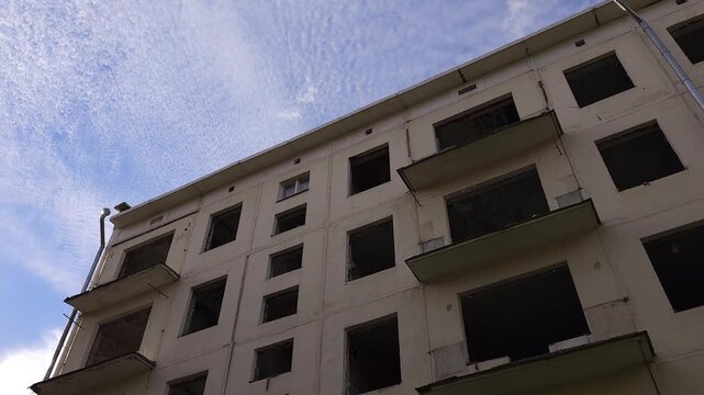 Low angle view of an aging apartment building with empty windows and balconies, illustrating deteriorating housing stock, demolition and replacement through urban renewal
