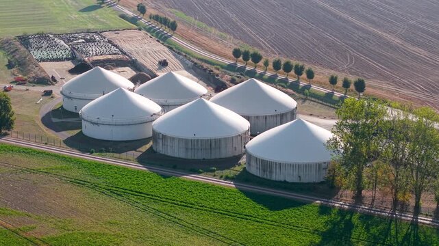Aerial drone view of biogas production facility with large anaerobic digesters and agricultural fields in Germany. Renewable energy plant converts organic waste into sustainable fuel and electricity