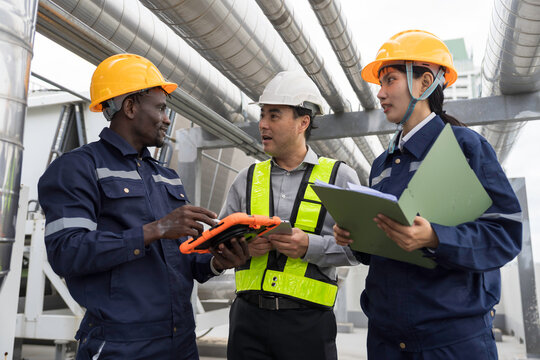 Multiethnic group technicians, supervisor inspect building ventilation system, pipeline system on rooftop. Diverse team HVAC engineers discussing maintenance inspection of air conditioning ductwork