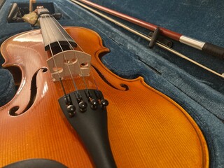 Close-up of violin with bow in blue velvet case, low angle view of bridge and strings © Bosko Martinovic