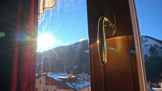 Morning sun shines brightly through a window onto a snowy mountain village scene.
