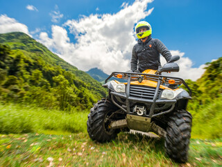 Outdoor recreation, ATV rider drives an all-terrain vehicle across a mountain landscape, combining off-road adventure, motorsport, tourism and active travel. © Grispb