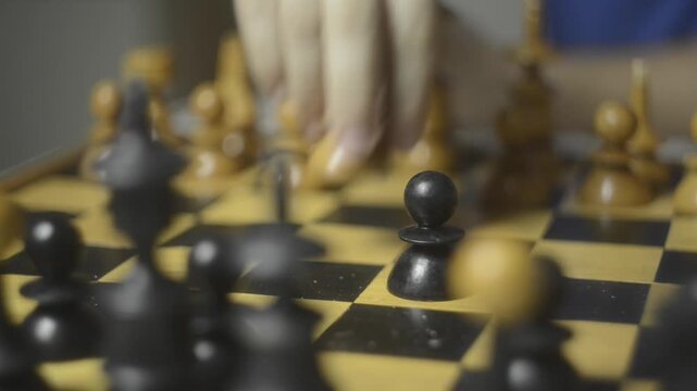 A close-up view captures a hand making a strategic move on a chessboard