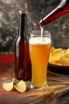 front view bottle of bear pouring up into the glass with cips on dark background alcohol photo snack color meat