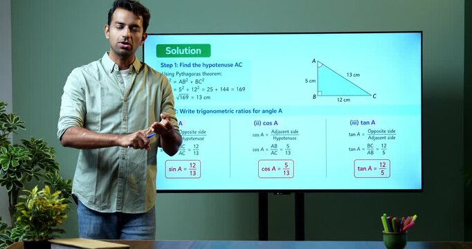 Young Indian male mathematics teacher explaining trigonometry on a large digital TV whiteboard for online classes, covering math education, geometry and modern e-learning.