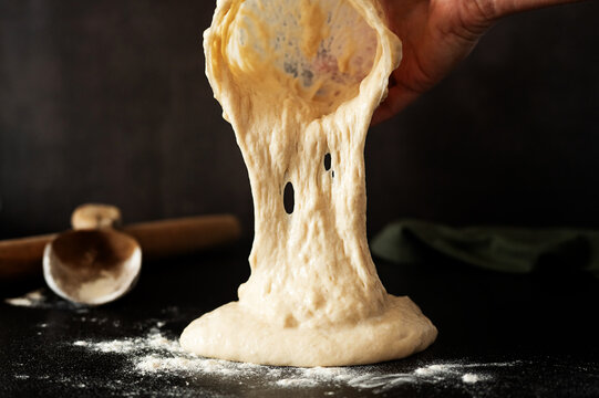 Baker removing fermented sourdough starter or dough out from a jar.