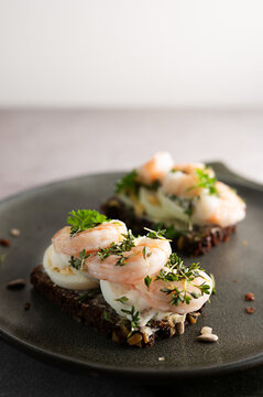 Seeded rye bread with egg, shrimps, and garden cress garnish.
