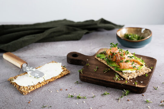 Preparing a healthy crispbread sandwich with avocado and smoked salmon.