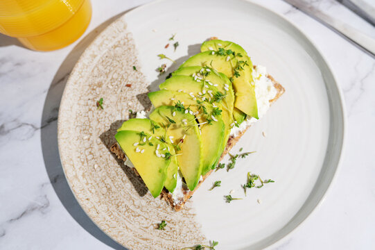 Sunlit breakfast plate with avocado cress crispbread and citrus juice.