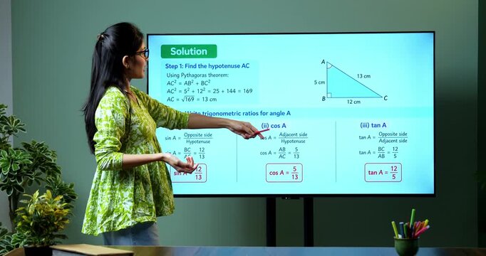Young Indian female mathematics teacher explaining trigonometry on a large digital TV whiteboard for online classes, covering math education, geometry and modern e-learning.
