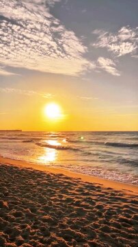 Stuning sunset view over a peaceful sandy beach with gentle ocean waves and dramatic clouds in the evening sky.   