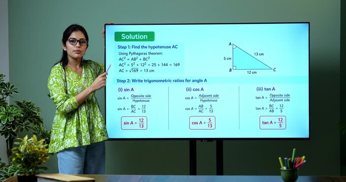 Young Indian female mathematics teacher explaining trigonometry on a large digital TV whiteboard for online classes, covering math education, geometry and modern e-learning.