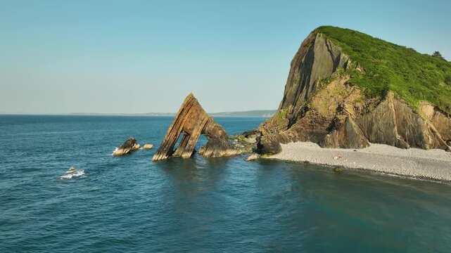 Aerial tracking shot of Blackchurch Rock arch on a Devon beach
