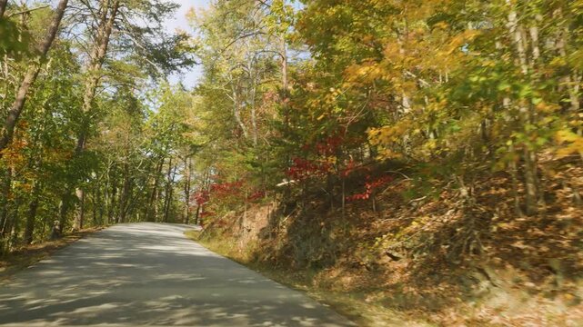 Vibrant Fall Park Forest. POV Driving Car at Mountains Road With Autumn Fall Foliage on Trees Scenic Road With Colorful leaves. Driving Paris Mountain State Park, South Carolina on Sunny Autumn Day.