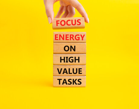 Focus energy on high value tasks symbol. Concept words focus energy on high value tasks on wooden blocks. Businessman hand. Beautiful yellow background. Business concept. Copy space.