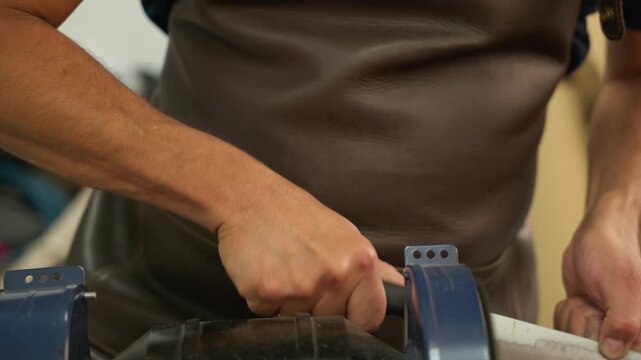 Man sharpen a knife on a workshop machine