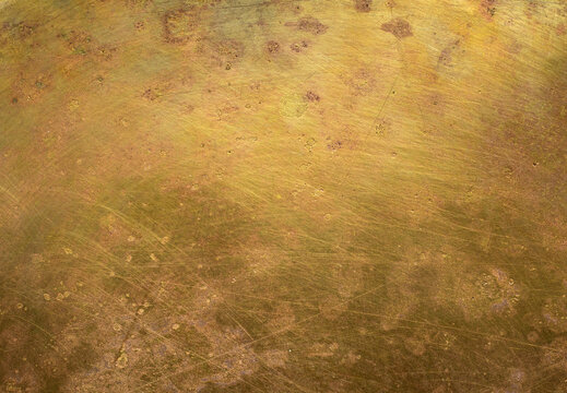 Close-up of aged brass with rich patina, oxidation, scratches, stains, and traces of time. A painterly metallic surface with intricate textures, weathered details, and warm antique tones.