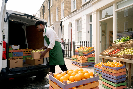 Black grocer unloads fresh fruit outside neighborhood shop
