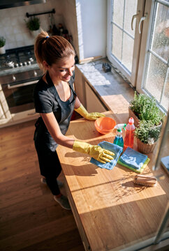 Woman clean kitchen countertop with cloth and detergent