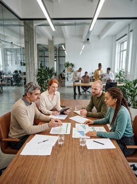 Diverse team review financial reports in modern office