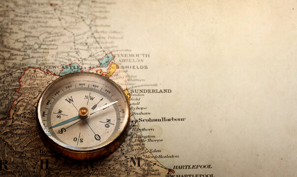 Vintage brass compass on an old England geographic map.  Antique navigation instrument for travel, exploration, geography and discovery concept.
