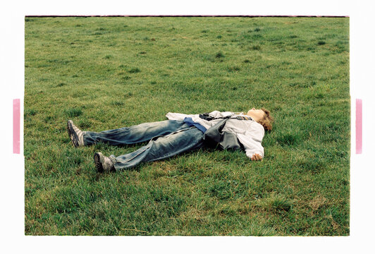 A teenager sprawled on grass, camera resting on chest