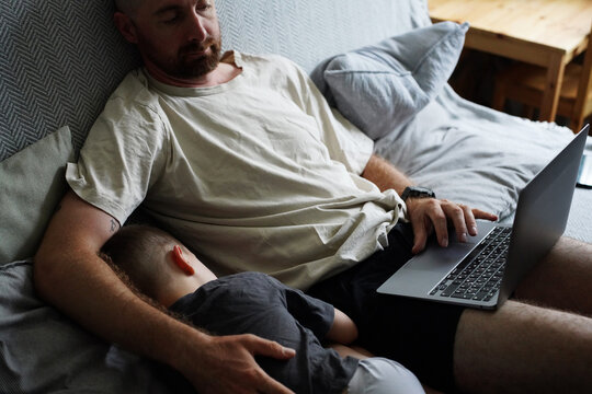 Father Resting with Sleeping Son and Laptop