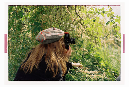 A woman photographs wild grasses with a film camera