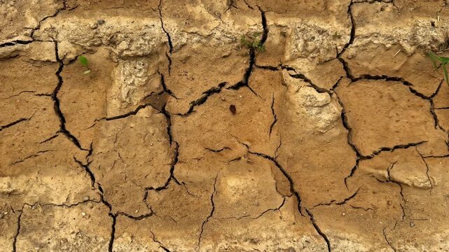 Dry cracked earth forms deep fissures across an arid landscape, illustrating drought, water scarcity and severe soil desiccation - top view