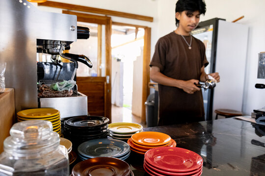 Indonesian barista working behind counter in local coffee shop