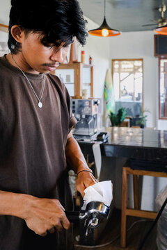 Indonesian barista cleaning portafilter in local coffee shop