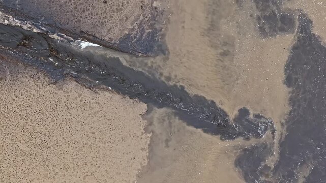 Aerial view of dirty water and toxic chemical spill flowing from a pipe into a river