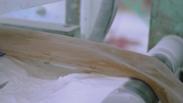 Extruded rubber tube passing over a roller through white talc powder to prevent sticking in a rubber band factory
