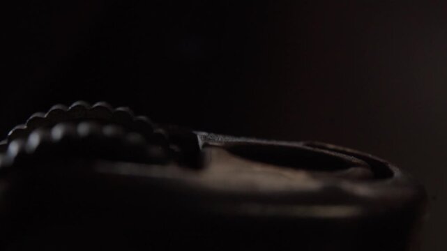 Igniting lighter wheel creating spark during flame ignition with finger pressing mechanism in dark setting showing metal texture and warm light against black background.
