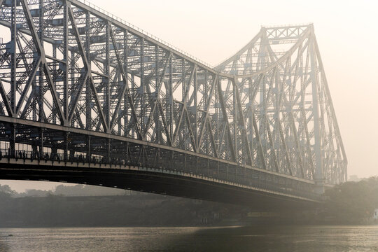 Large steel truss bridge spanning a calm river in warm morning haze, West Bengal, Kolkata, India