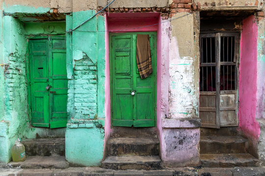 Row of old green wooden doors set in mint green and pink painted walls with a hanging cloth, West Bengal, Kolkata, India