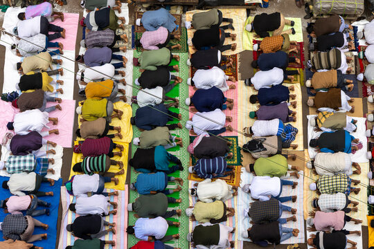 Aerial view of rows of men praying on colorful mats along a street during Friday prayer, West Bengal, Kolkata, India