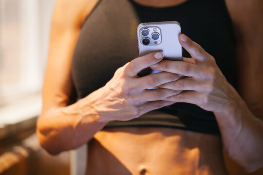 Close-up of woman using smartphone in sports bra indoors