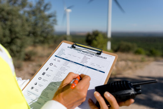 Female engineer inspect wind turbine field checklist on site