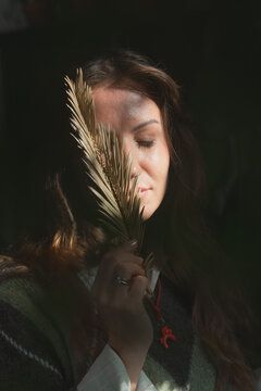 Woman with closed eyes holding dried palm leaf