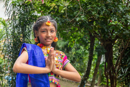 Young Hindu girl in traditional dress performing namaste