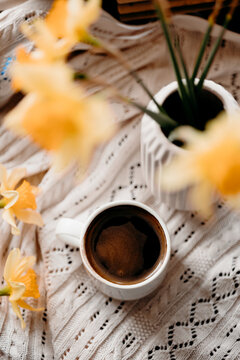 Coffee cup with daffodil flowers on knitted blanket