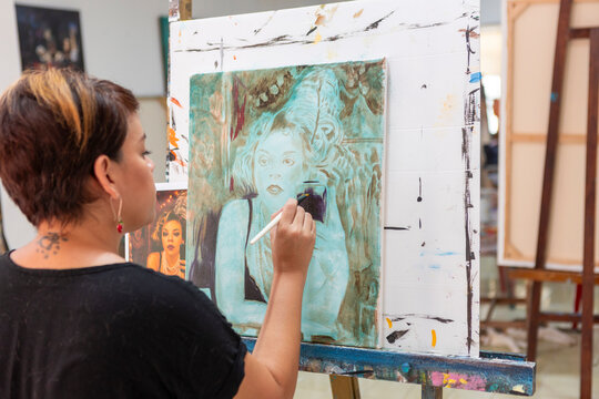 Woman painting artwork during art lesson in studio