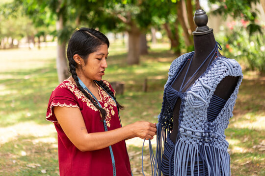 Artisan adjusts handmade macrame vest on dress form