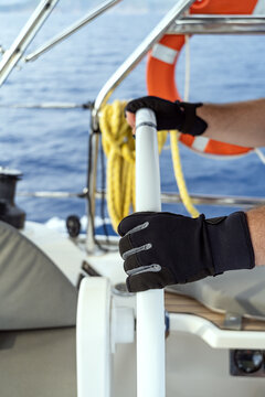 Skipper steering yacht with gloved hands at sea