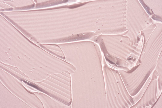 Translucent cosmetic gel serum texture on pink background
