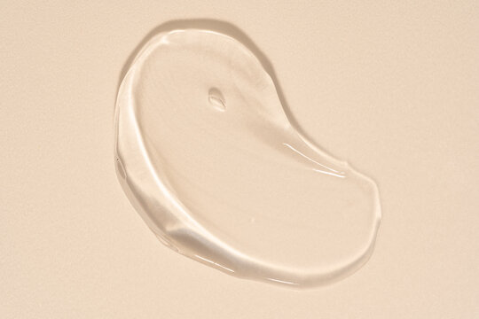 Transparent cosmetic gel serum texture on beige background